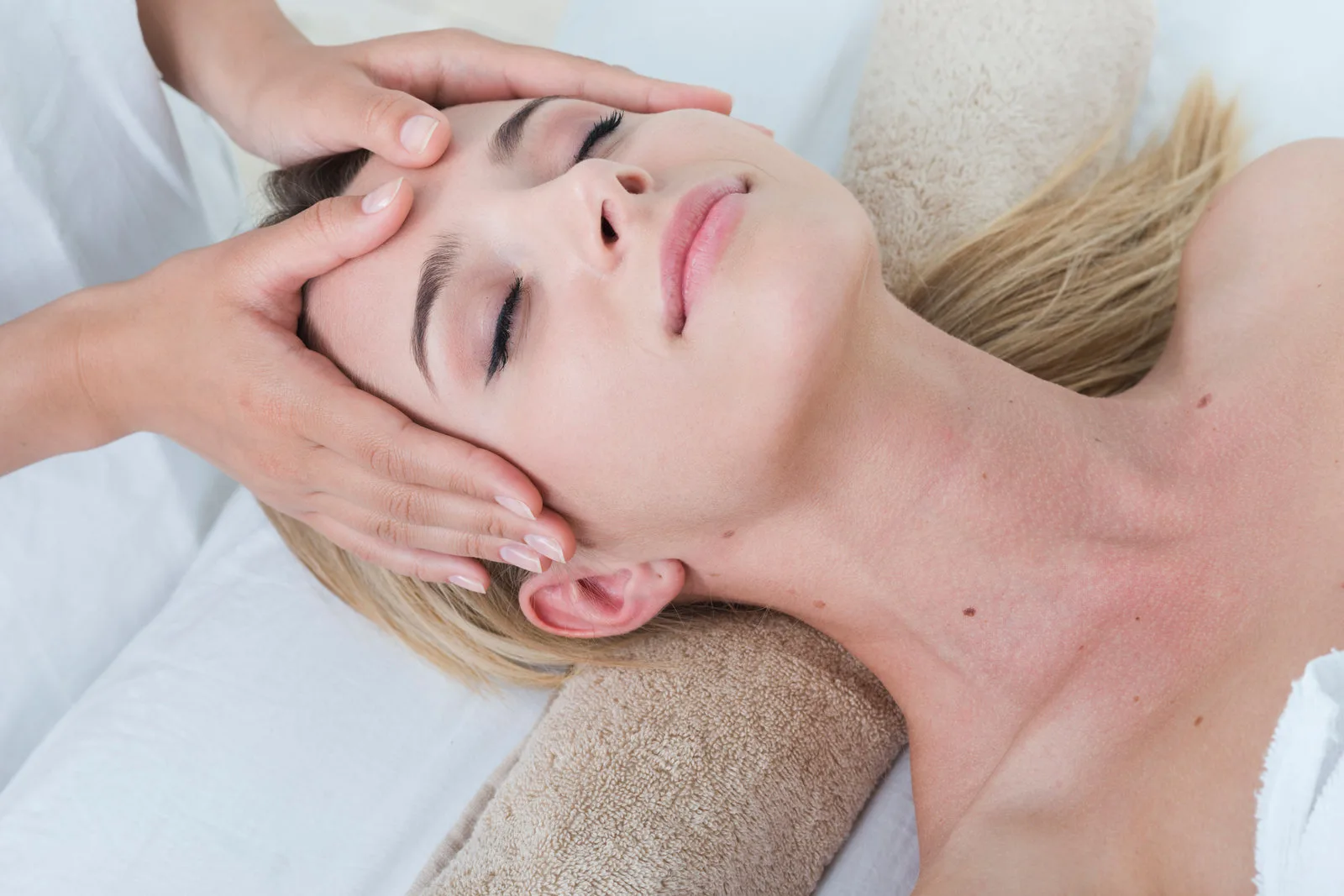 A relaxed woman receiving a gentle head massage